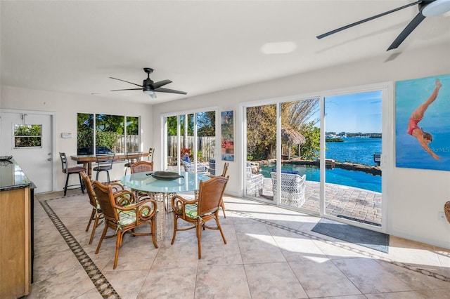 sunroom featuring ceiling fan and a water view