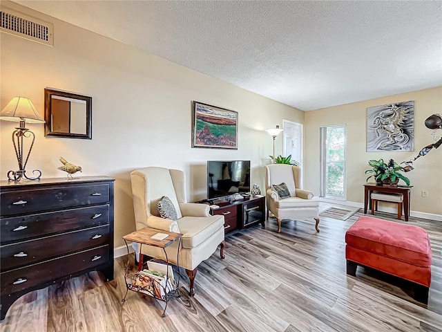 living room featuring light hardwood / wood-style flooring and a textured ceiling