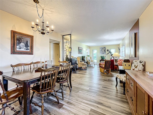 dining space featuring an inviting chandelier, a textured ceiling, and light wood-type flooring