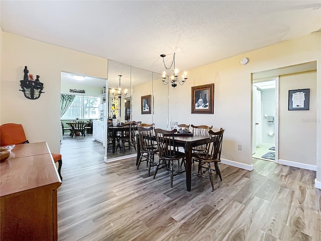 dining space with an inviting chandelier, wood-type flooring, and a textured ceiling