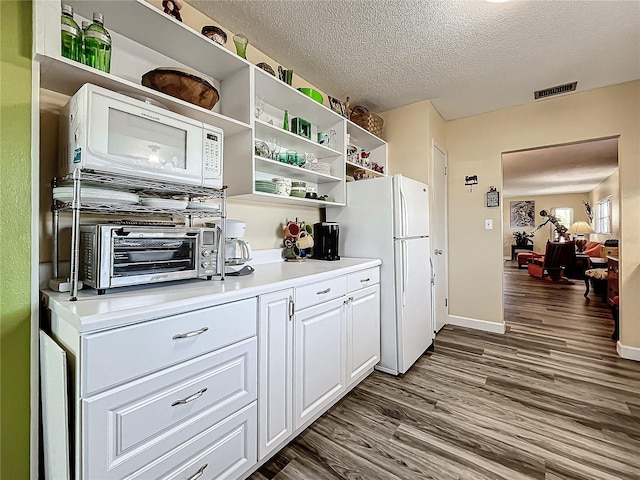 kitchen with dark wood-type flooring, white appliances, a textured ceiling, and white cabinets