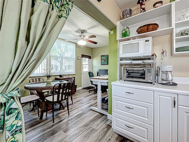 kitchen featuring white cabinetry, light wood-type flooring, ceiling fan, and a textured ceiling