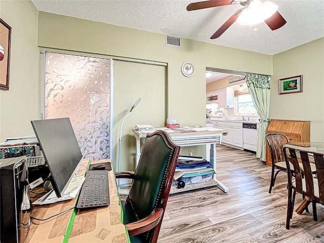 office area featuring ceiling fan, light hardwood / wood-style flooring, and a textured ceiling