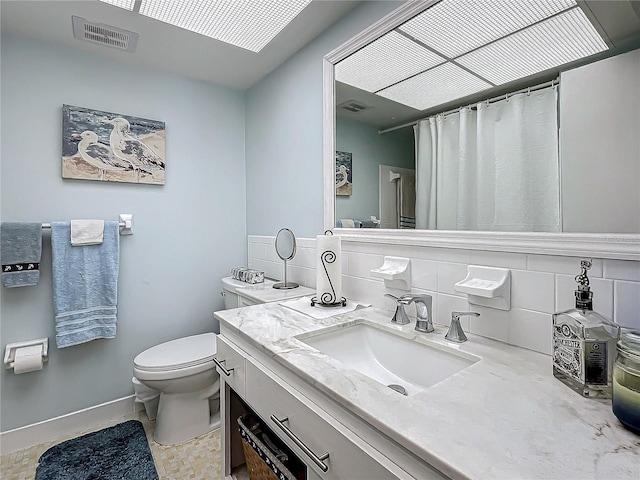 bathroom featuring vanity, backsplash, and toilet