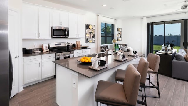 kitchen with a center island with sink, a kitchen bar, sink, white cabinetry, and stainless steel appliances