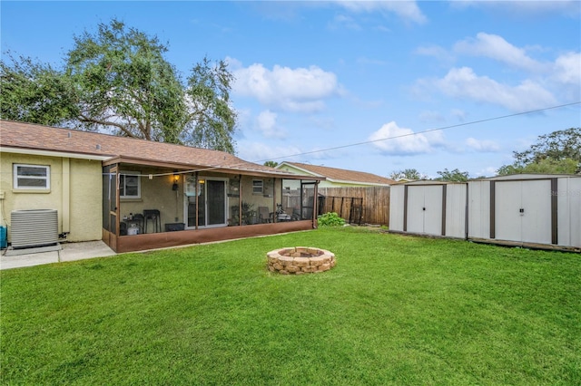 view of yard with an outdoor fire pit, a shed, central air condition unit, and a sunroom