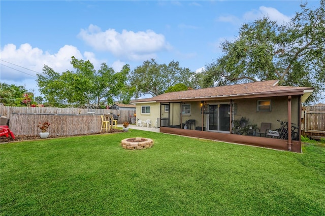 back of house with a yard and a fire pit