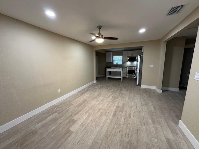 unfurnished living room with ceiling fan, light hardwood / wood-style floors, and sink