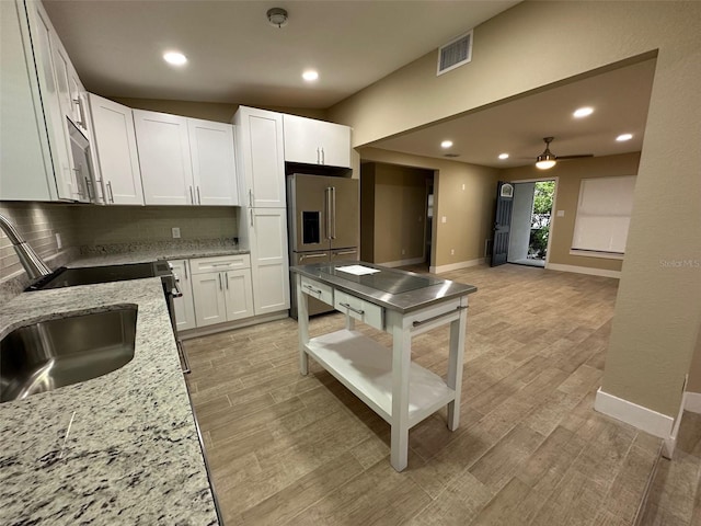 kitchen with ceiling fan, backsplash, high end refrigerator, white cabinetry, and light stone countertops