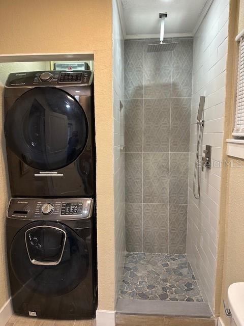 laundry area with stacked washer and dryer and ornamental molding