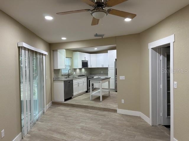 kitchen featuring white cabinetry, light hardwood / wood-style floors, ceiling fan, stainless steel appliances, and sink