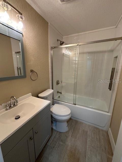 full bathroom featuring toilet, combined bath / shower with glass door, wood-type flooring, a textured ceiling, and ornamental molding