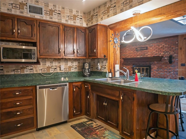 kitchen featuring sink, a breakfast bar area, appliances with stainless steel finishes, kitchen peninsula, and pendant lighting