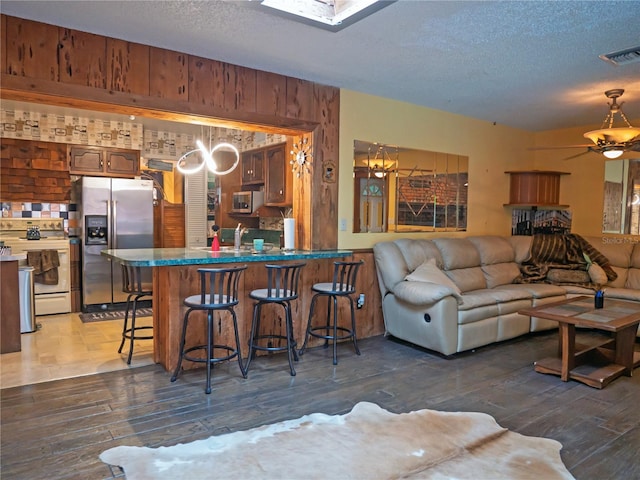 living room featuring ceiling fan, dark hardwood / wood-style floors, and a textured ceiling