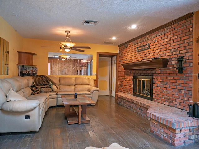 living room featuring dark hardwood / wood-style floors, ceiling fan, a fireplace, and a textured ceiling