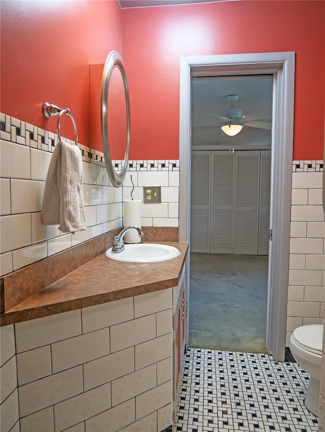 bathroom with vanity, toilet, and tile walls