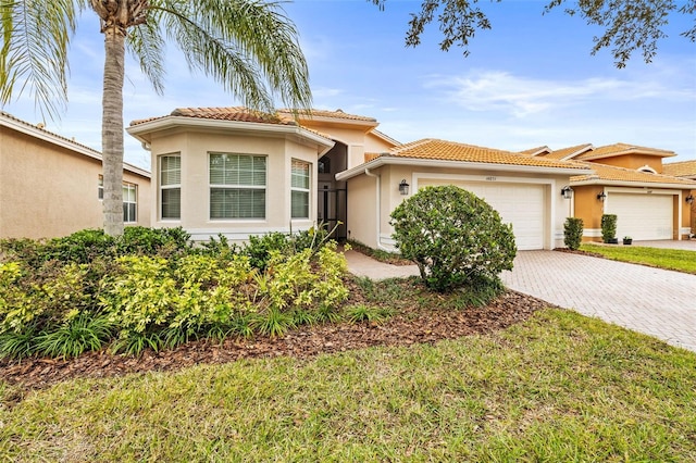 mediterranean / spanish house featuring a garage and a front lawn