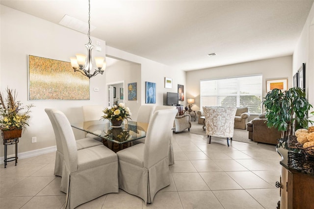 dining space with light tile patterned floors and an inviting chandelier