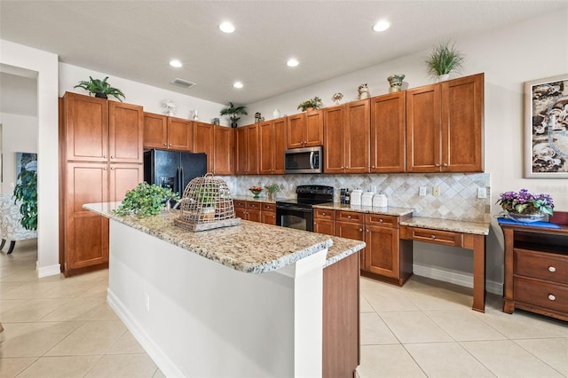 kitchen featuring tasteful backsplash, light tile patterned floors, light stone countertops, a kitchen island, and black appliances