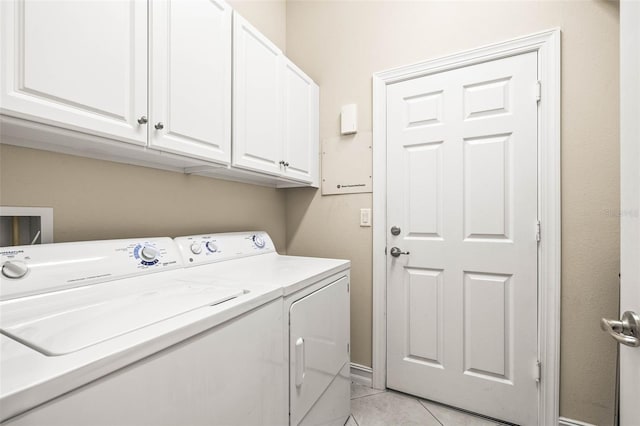 washroom with light tile patterned flooring, cabinets, and washer and dryer