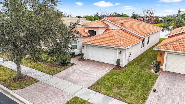 mediterranean / spanish home featuring a garage, a water view, and a front yard