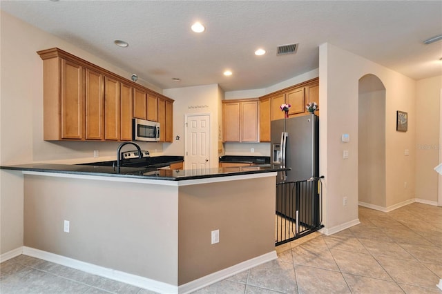 kitchen featuring kitchen peninsula, light tile patterned floors, stainless steel appliances, and a textured ceiling