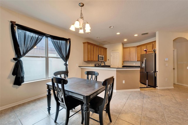 tiled dining room with an inviting chandelier