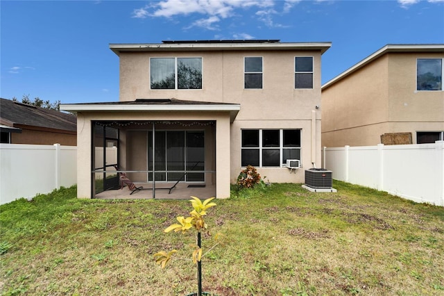 rear view of property with a patio area, a sunroom, a lawn, and solar panels