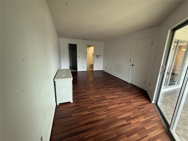 spare room featuring wood finished floors, a textured ceiling, and baseboards