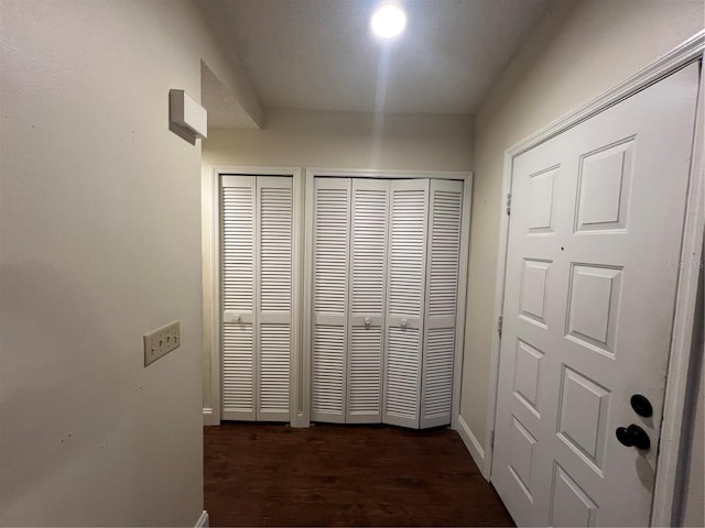 corridor featuring baseboards and dark wood-style floors