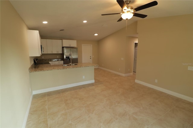 kitchen with appliances with stainless steel finishes, white cabinetry, kitchen peninsula, vaulted ceiling, and stone counters