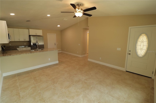 kitchen featuring lofted ceiling, ceiling fan, light stone countertops, stainless steel appliances, and white cabinets