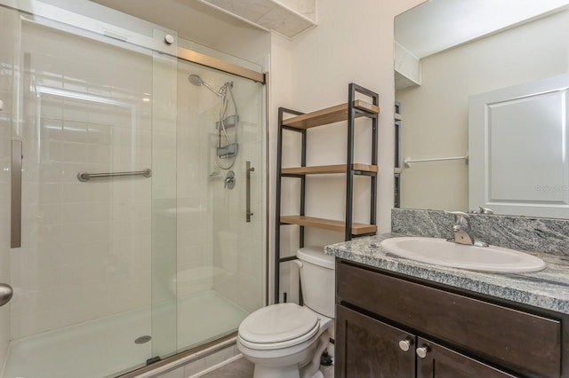 bathroom with a shower with door, vanity, and toilet