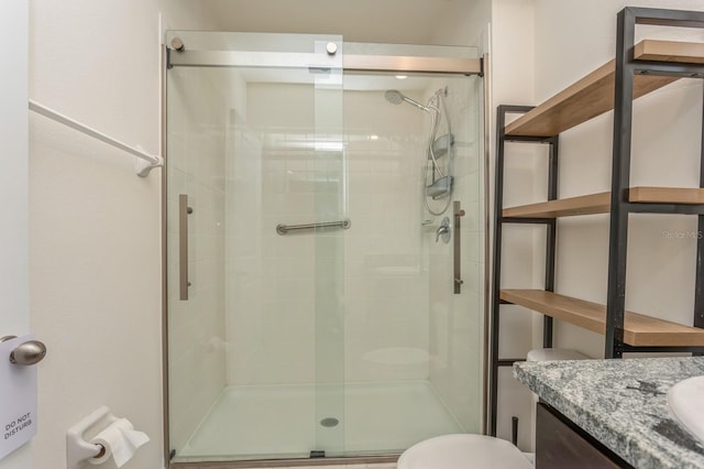 bathroom featuring vanity, toilet, and a shower with door