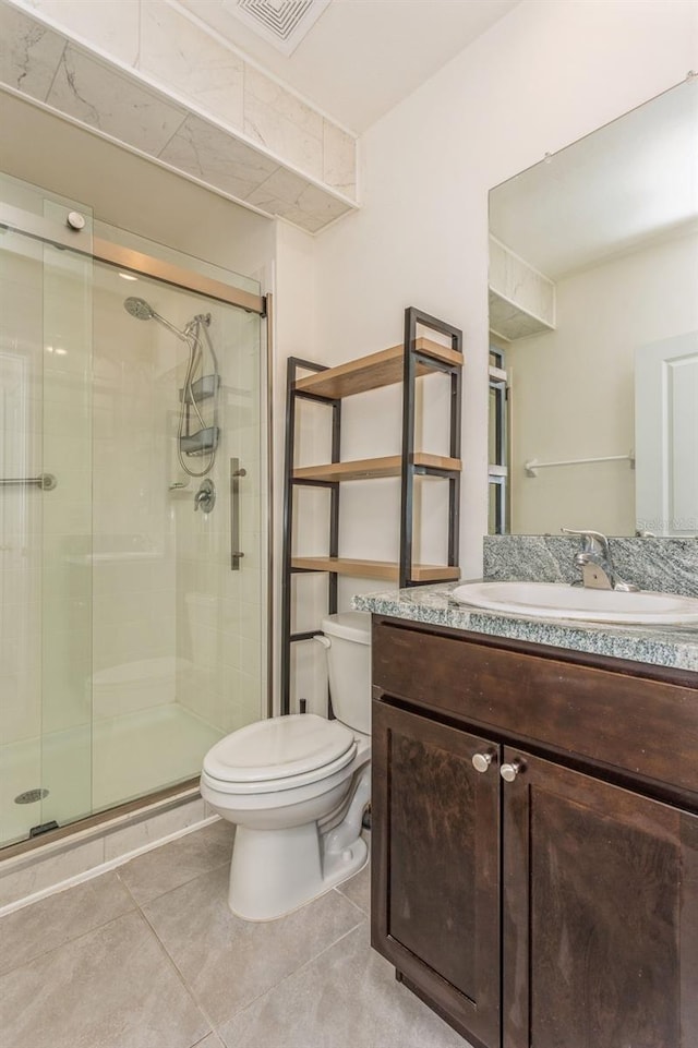 bathroom with vanity, tile patterned floors, a shower with door, and toilet