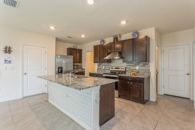 kitchen featuring sink, stone counters, appliances with stainless steel finishes, a center island with sink, and light tile patterned flooring