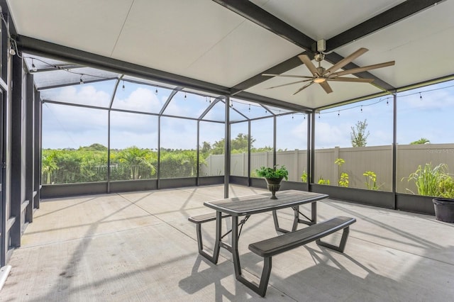 unfurnished sunroom featuring ceiling fan and beam ceiling