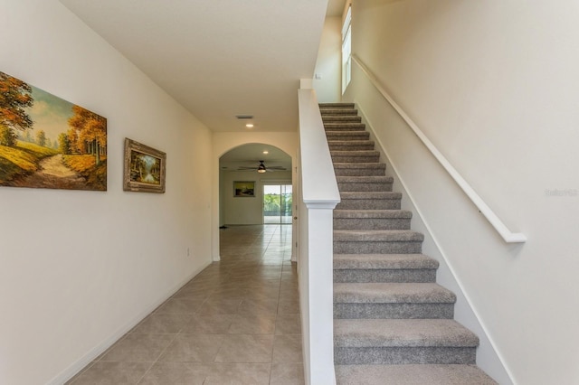 staircase featuring ceiling fan and tile patterned flooring