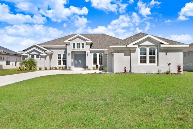 view of front of property with roof with shingles, driveway, a front lawn, and stucco siding