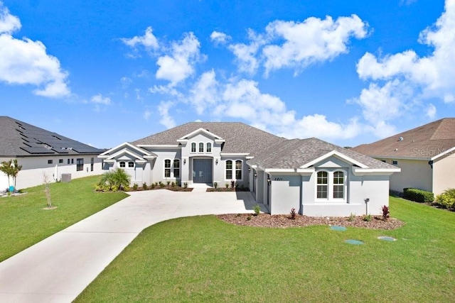 view of front facade featuring driveway, central AC, a front yard, and stucco siding