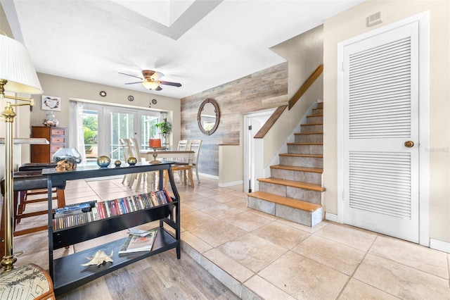 interior space featuring ceiling fan, french doors, and wooden walls