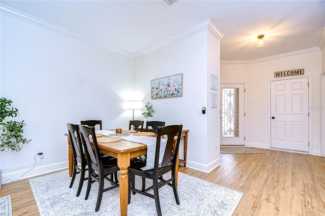 dining space featuring crown molding and light hardwood / wood-style floors