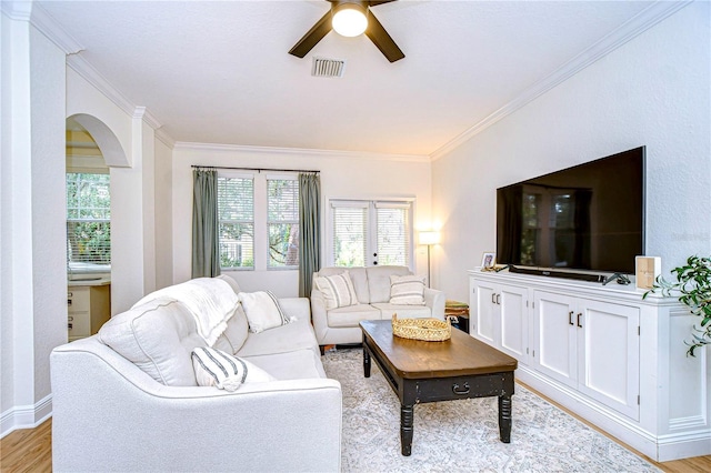 living room featuring ceiling fan, ornamental molding, and light wood-type flooring