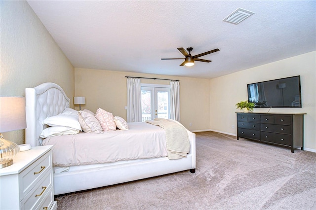 bedroom featuring a textured ceiling, french doors, access to outside, ceiling fan, and light colored carpet