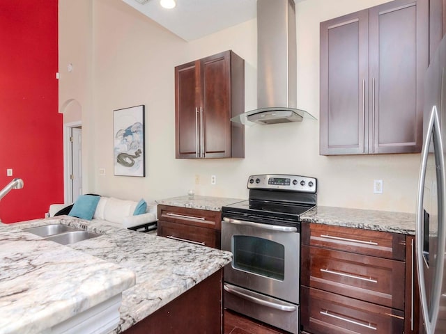 kitchen featuring light stone counters, wall chimney exhaust hood, stainless steel appliances, and sink