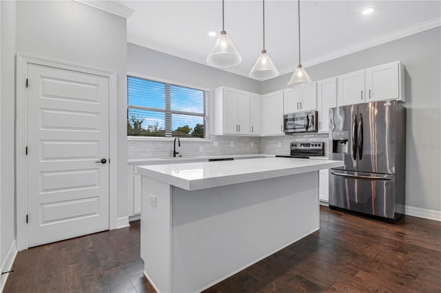 kitchen with white cabinets, hanging light fixtures, appliances with stainless steel finishes, and a kitchen island