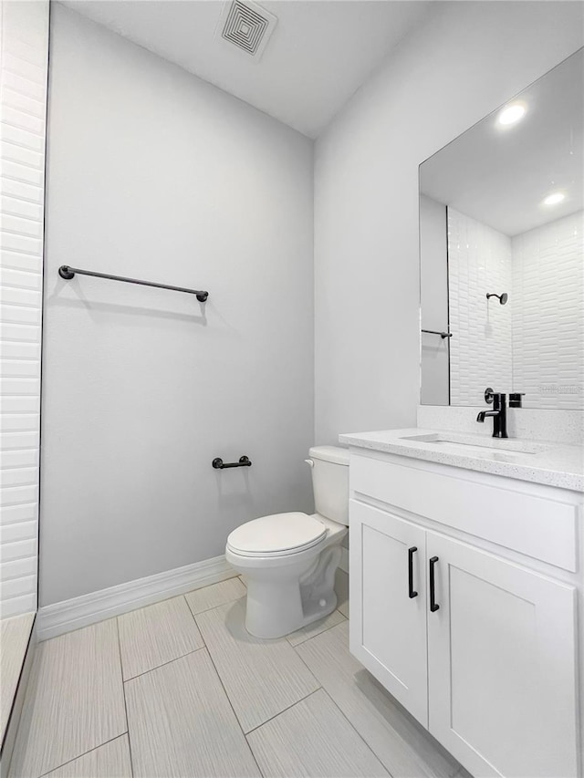 bathroom with vanity, toilet, and a tile shower