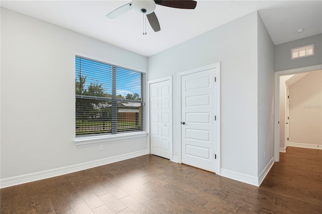 unfurnished bedroom with multiple closets, ceiling fan, and dark hardwood / wood-style flooring