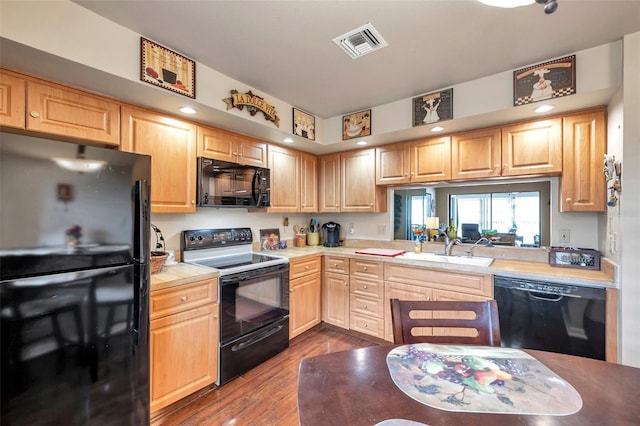 kitchen with light brown cabinetry, sink, wood-type flooring, and black appliances