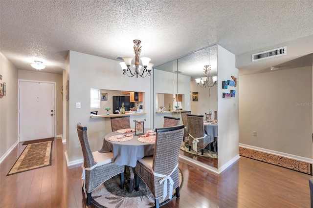 dining room featuring a textured ceiling, an inviting chandelier, and hardwood / wood-style floors